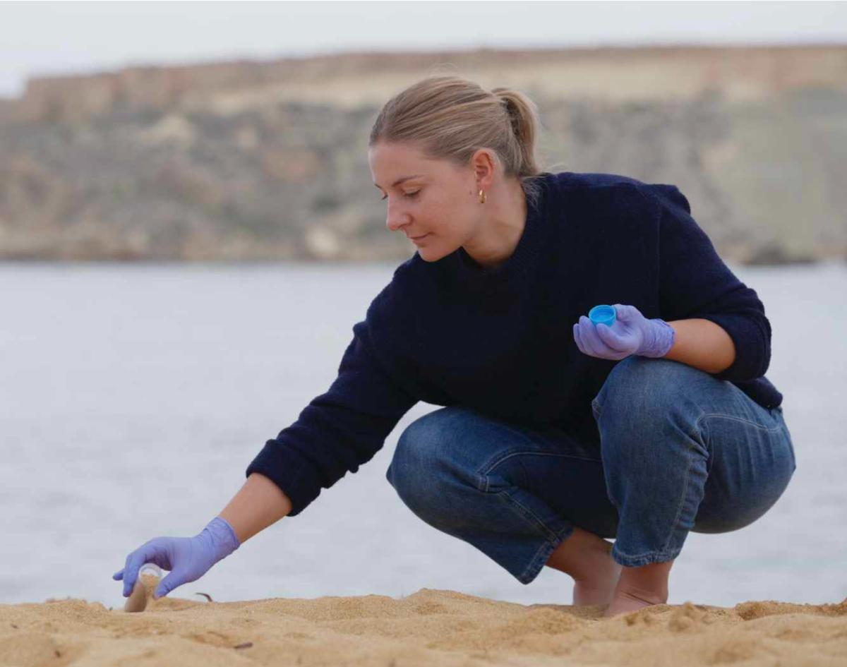 Researcher taking a sediment sample on the beach